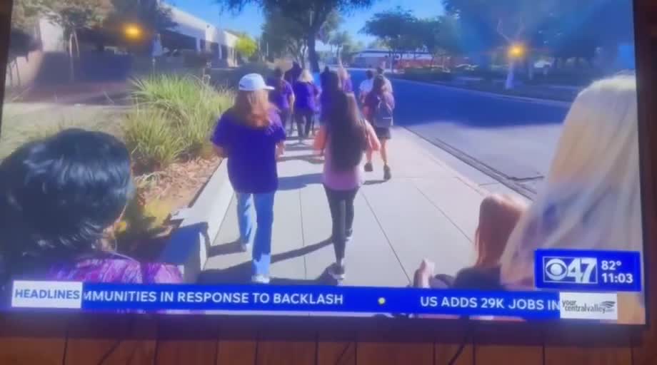 News footage of Arise community members walking together in purple awareness shirts